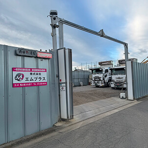 株式会社エムプラスの敷地入り口と構内に停車するトラック