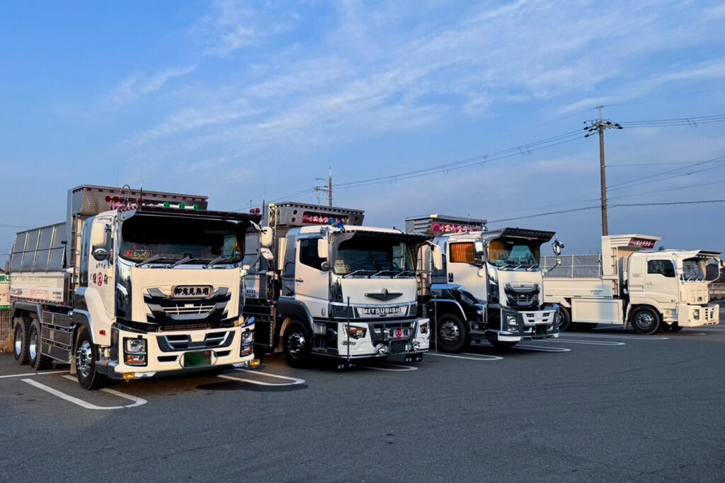 数台の大型ダンプトラックが整列して駐車されている様子